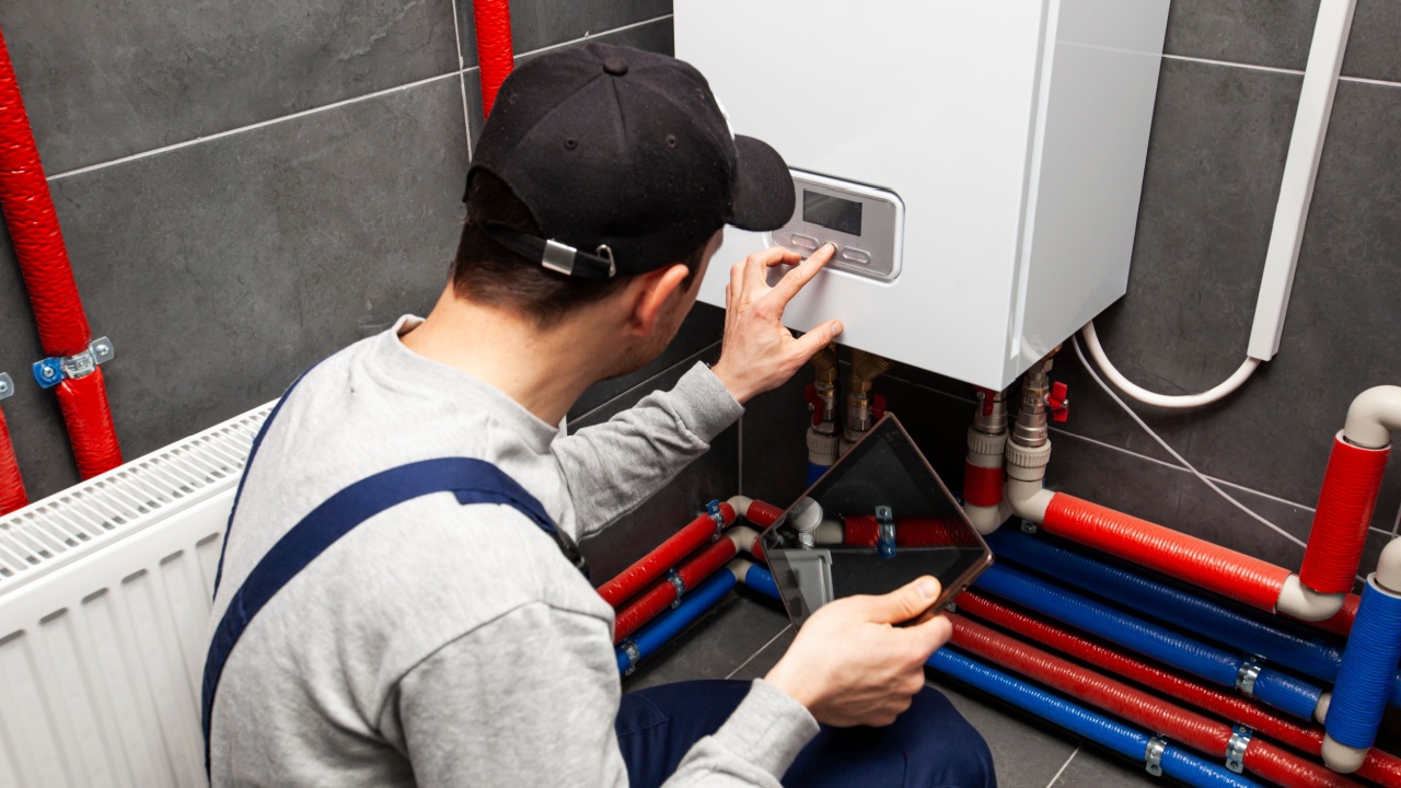 The technician checking the heating system in the boiler room with tablet in hand