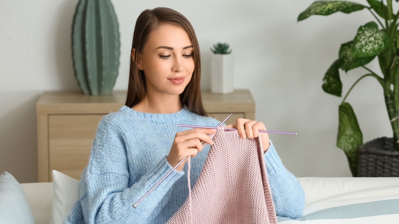 Young woman knitting warm sweater at home