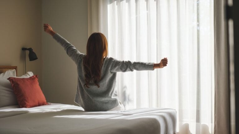 Rear view image of a woman do stretching after waking up in bedroom