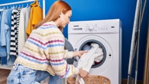 Young caucasian woman washing clothes at laundry room