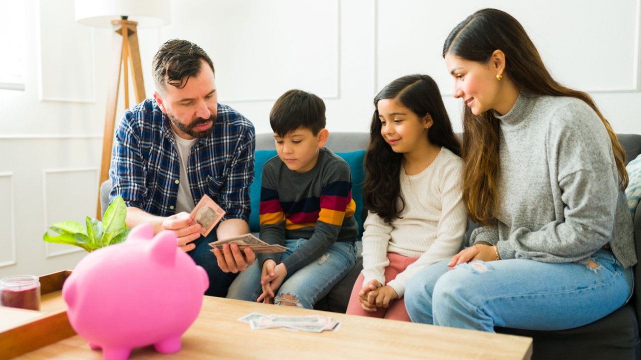 Caring parents teaching financial education to their children while counting money together to put in the piggy bank