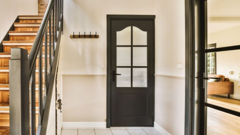 an entry way in a house with wood floors and black door leading up to the second floor