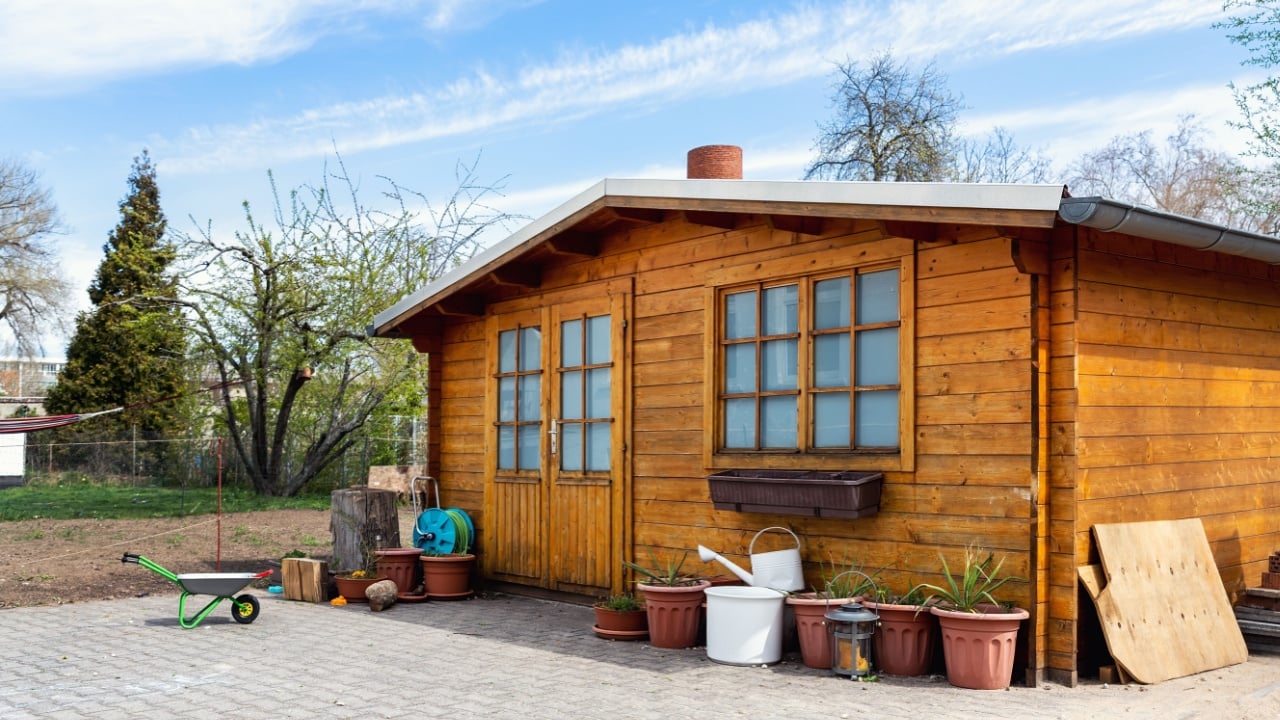 Small beautiful wooden house shed or storage hut for garden tools equipment and bicycles at backyard at beautiful american or european countryside backyard. Cozy rural yard stuff warehouse