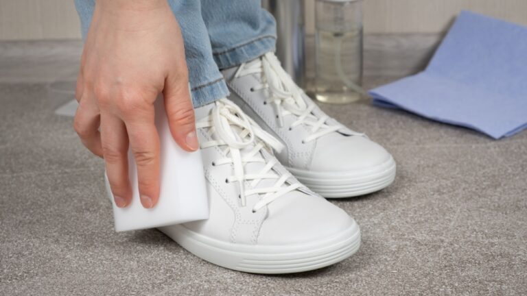 A woman cleans sneakers from dust and dirt with a melamine sponge.