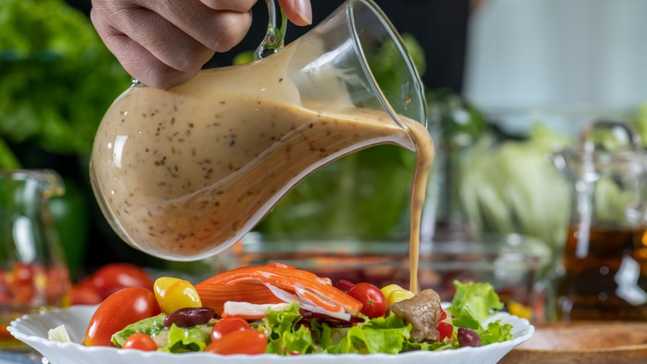 woman chef mix fresh baby cos salad and pour salad dressing in glass blow. Organic Vegetables mix all green salad In glass bowl. Breakfast fresh salad and clean vegetable.