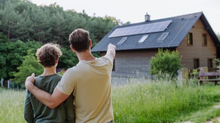 Father showing roof with solar panels to his son. Alternative energy, saving resources and sustainable lifestyle concept.