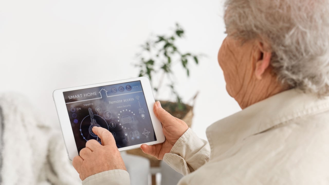 Senior woman using smart home security system control panel, closeup