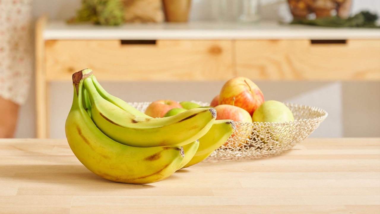 Banana and various fruits in the basket, decorative wooden kitchen interior. Woman background.