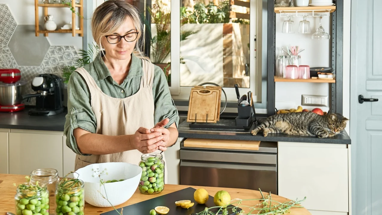 Woman preparing fermented olives in glass jar with slices of lemon, wild fennel and canning brine. Autumn vegetables canning. Healthy homemade food. Conservation of harvest.