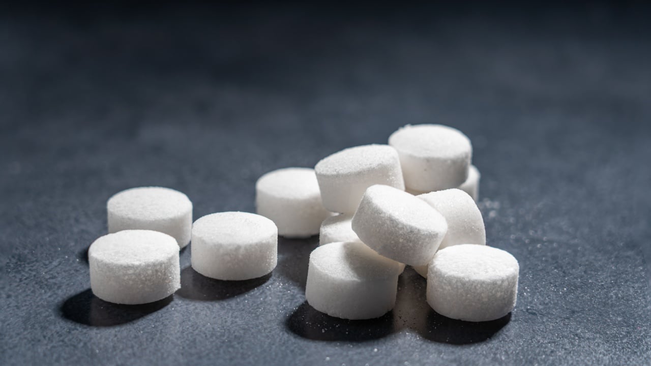 Round white sea salt tablets used in a water treatment appliance or dishwasher to soften the hard water by ion exchanger to prevent the building up of limescale. Copy space. Selective focus.