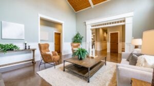 Living room interior with wooden beams hardwood flooring area rug furnishings sofa fireplace cabinets bohemian style houseplants arm chairs in natural colors