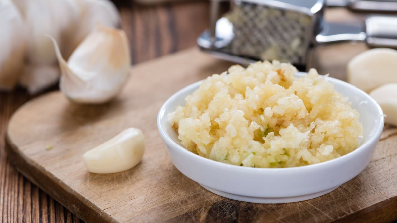 Fresh pressed Garlic (detailed close-up shot) on rustic wooden background