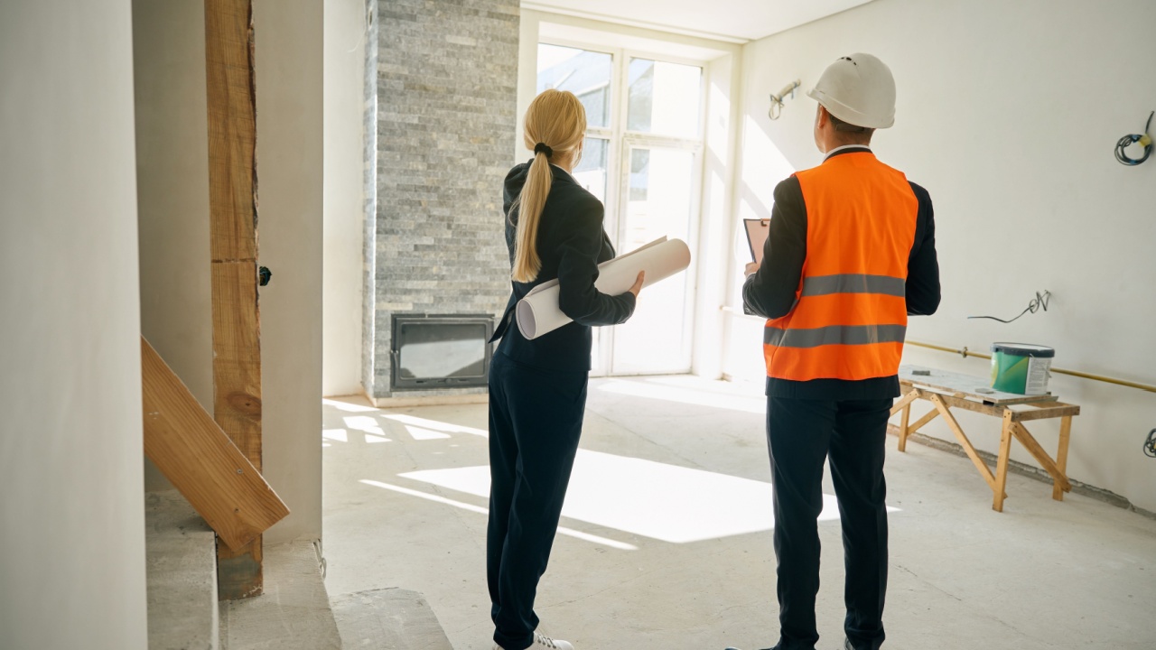Female client and male engineer standing in room under construction