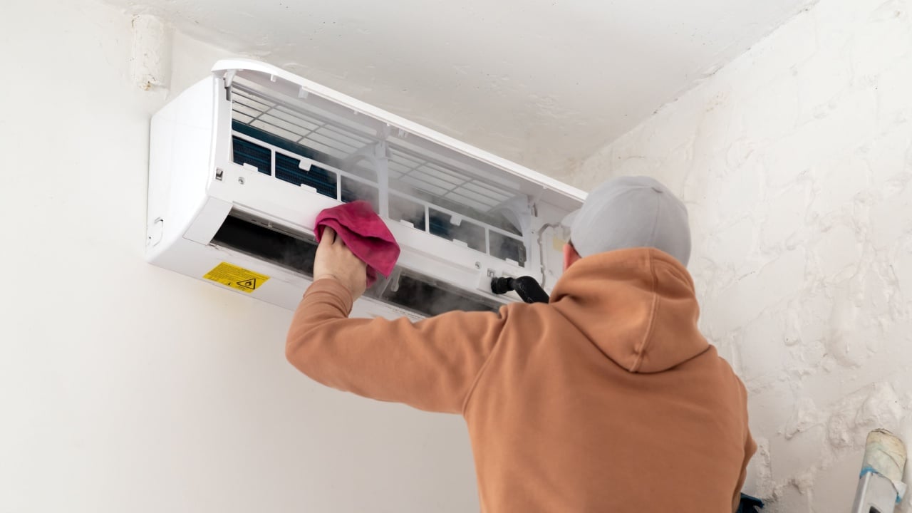 Technician service using vacuum cleaner to cleaning the air conditioner. Electrician repairing