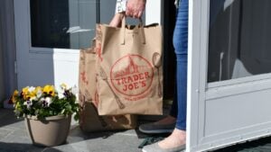 Staunton, VA April 9, 2020 Female picking up Trader Joe's grocery bags from porch that have been delivered