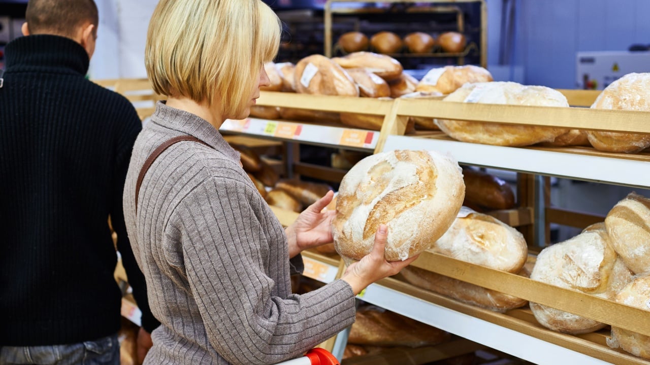 Young woman chooses bread in the store