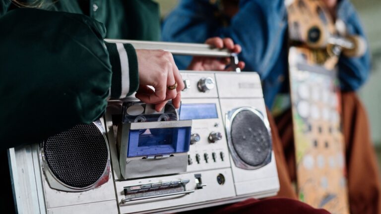 Closeup of unrecognizable girl inserting audio cassette into retro boombox to listen to music, copy space
