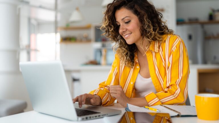 Confident businesswoman doing research over wireless laptop computer on desk while sitting in home office.