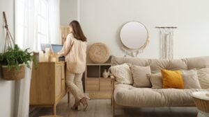 Young woman with record player on commode in cozy living room, back view