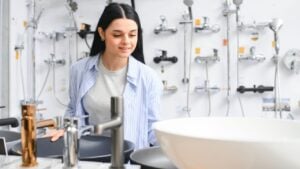 Woman inspects and chooses new kitchen or bath tap faucet at a hardware store.