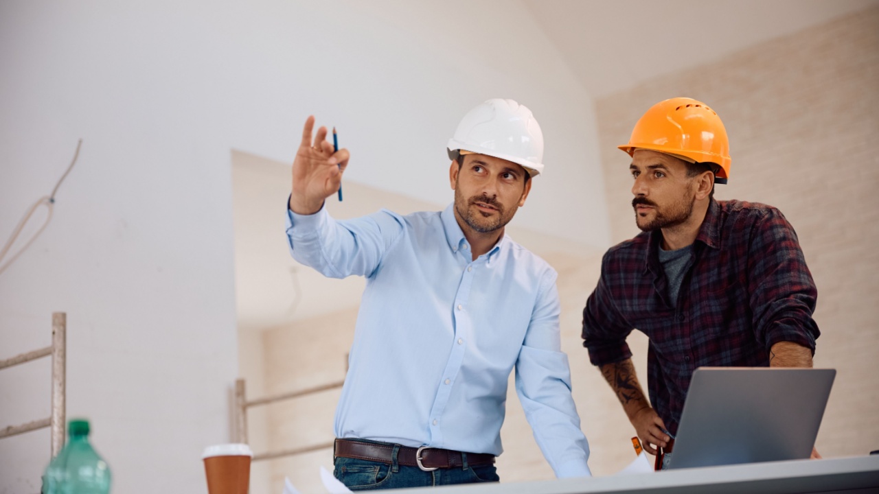Construction site worker going through blueprints with architect during housing development project
