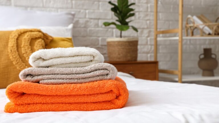 Middle age grey-haired man folding towels at laundry room