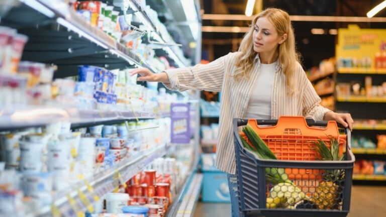 Young cool customer woman wear casual clothes shopping at supermaket store grocery shop buying with trolley cart choose products inside hypermarket.
