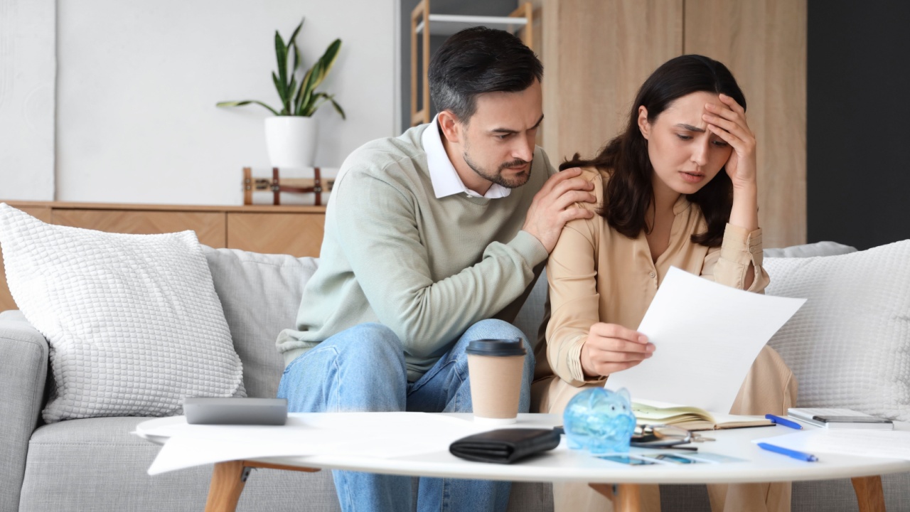 Worried young couple with bills at home.