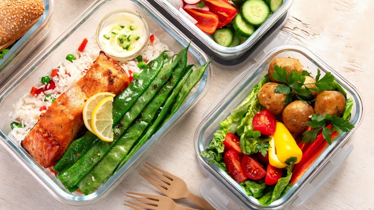 Different delicious healthy meals in containers on white background, top view. Panorama.