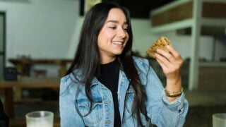 Happy young woman eating a delicious quesadilla at a mexican taco shop restaurant
