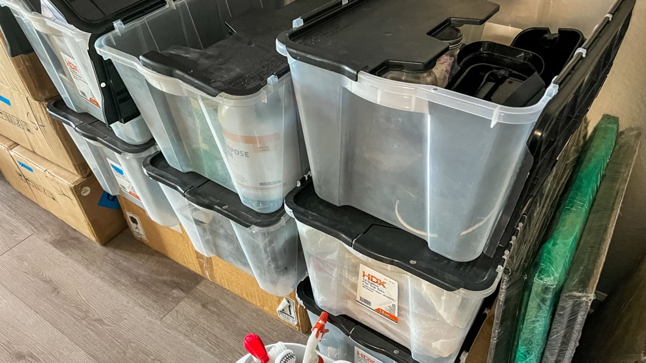 Castle Rock, Colorado, USA-April 11, 2023-A collection of clear plastic storage bins with black lids stacked against a wall used for organizing and packing during a moving process Some bins contain