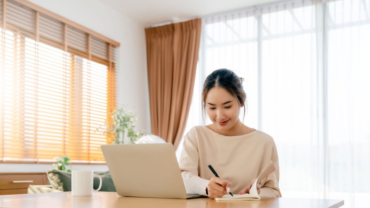 Young Asian woman happy positive cute beautiful business woman sit indoors in living room using laptop computer