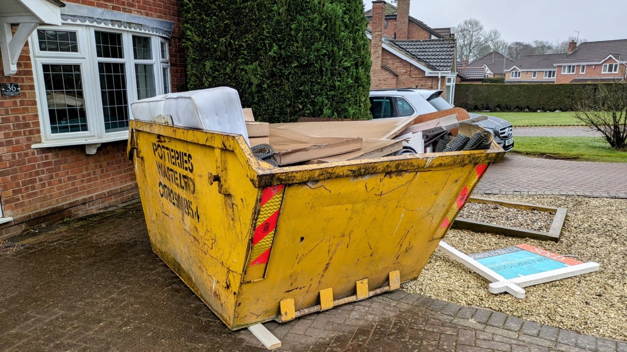 Trentham, Stoke-on-Trent, England, February 15th 2025. A yellow skip is on a drive, it is filled with a mattress, cardboard and building materials.