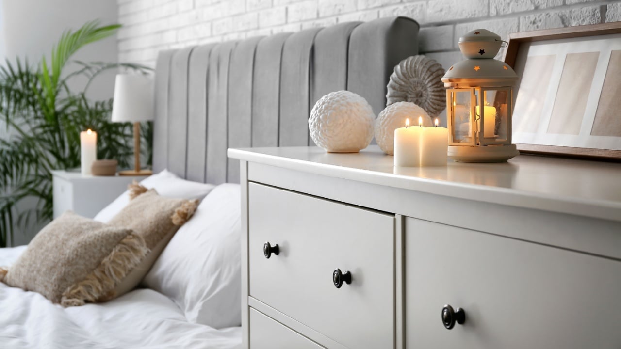Burning candles on chest of drawers in bedroom
