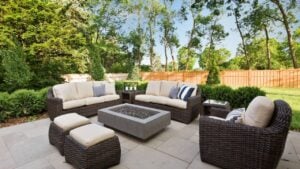 Luxury outdoor patio with wicker furniture, fire pit, and stone flooring. Modern patio design with comfortable outdoor sitting area, backyard patio with fire pit, and stylish furniture for outdoor living. Outdoor patio categorized as exteriors in buildings and landmarks