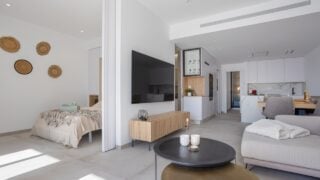 Torrevieja 6 April 2025: Spacious open-concept apartment featuring a living area, kitchen, and bedroom with modern furnishings and warm light tones.