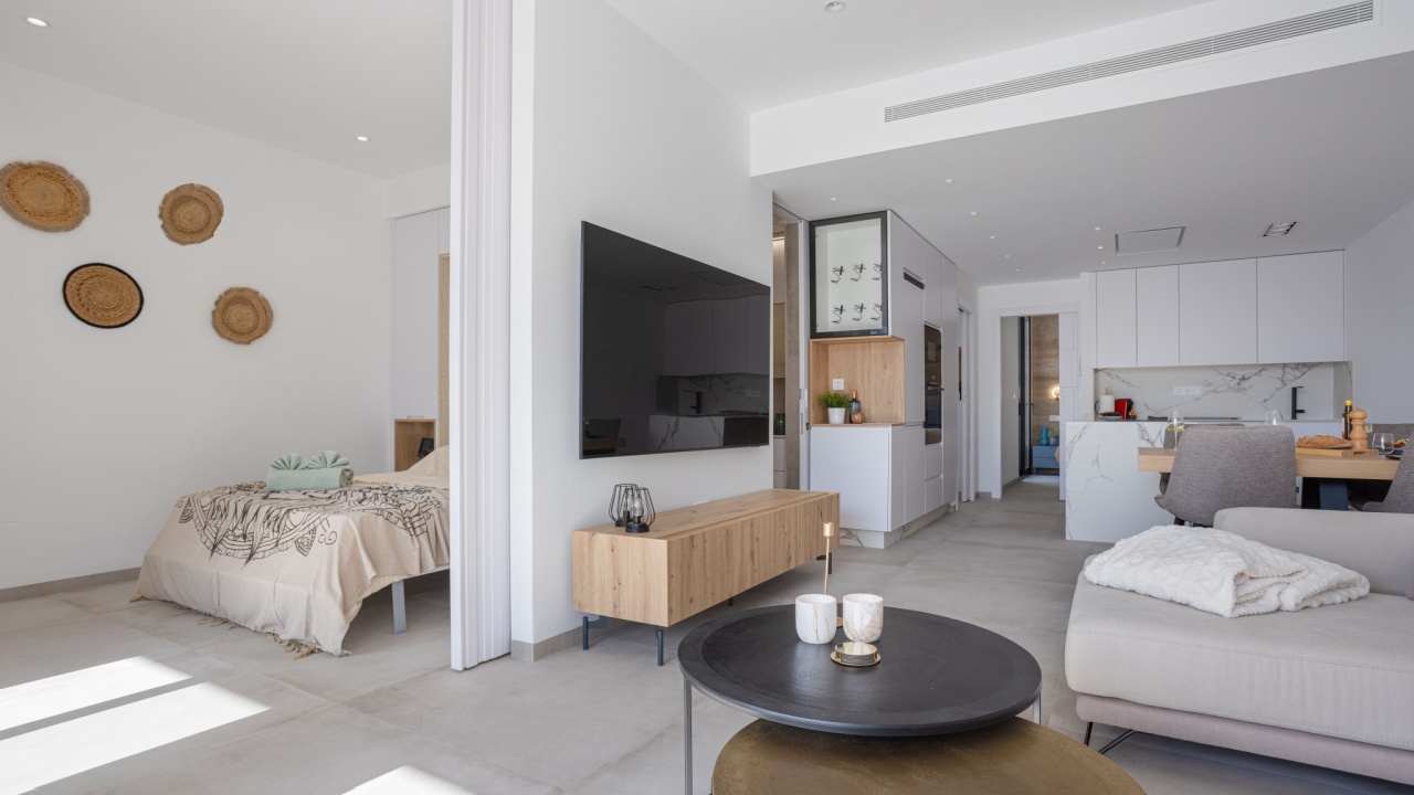 Torrevieja 6 April 2025: Spacious open-concept apartment featuring a living area, kitchen, and bedroom with modern furnishings and warm light tones.