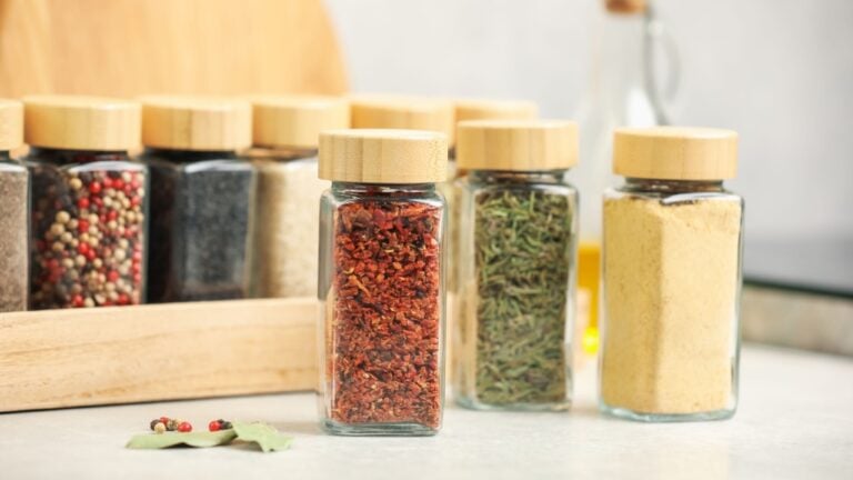 Different aromatic spices in jars on light grey table indoors