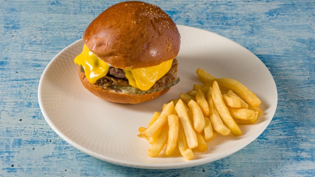 Smash burger with cheddar cheese and caramelized onions, served with fries