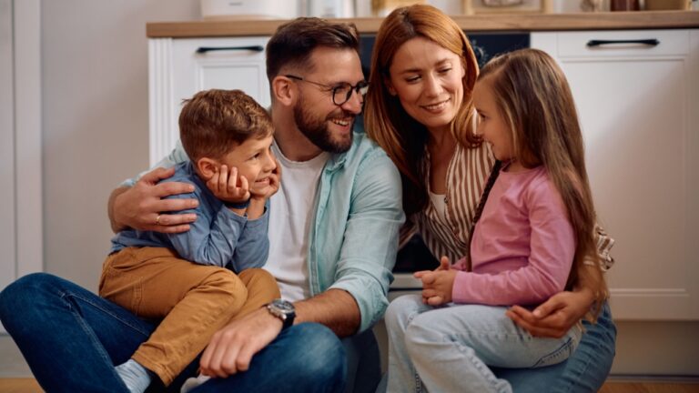 Happy parents talking to their kids while relaxing at home.