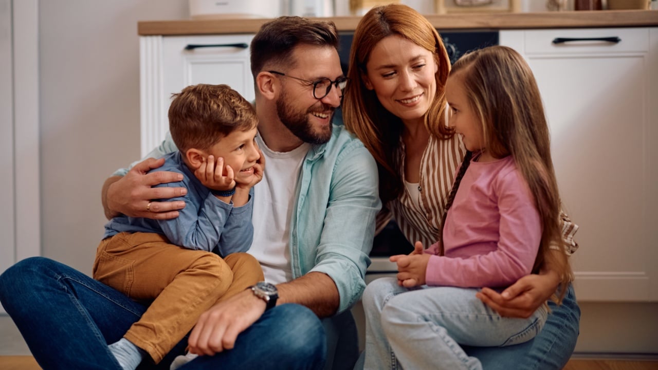 Happy parents talking to their kids while relaxing at home.