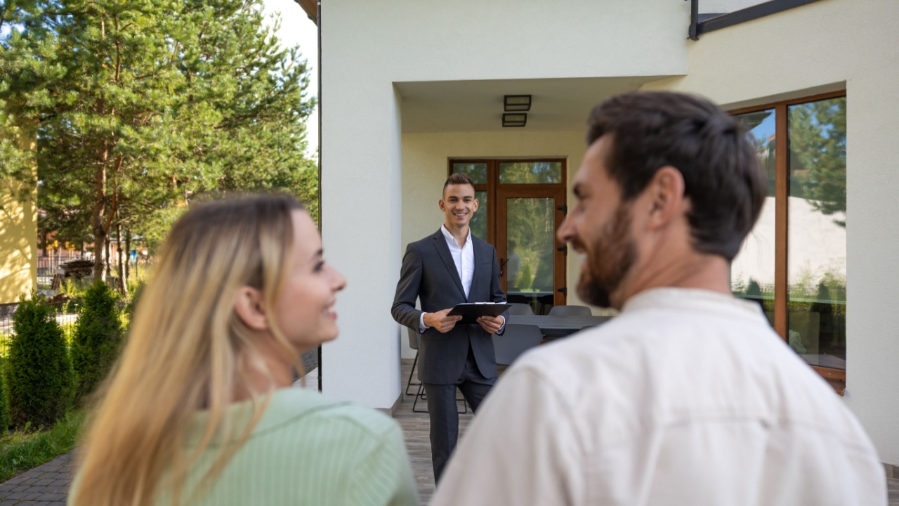 Real estate agent presenting house to couple outside property