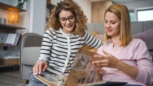 Two female friends looking at an old photo album at home
