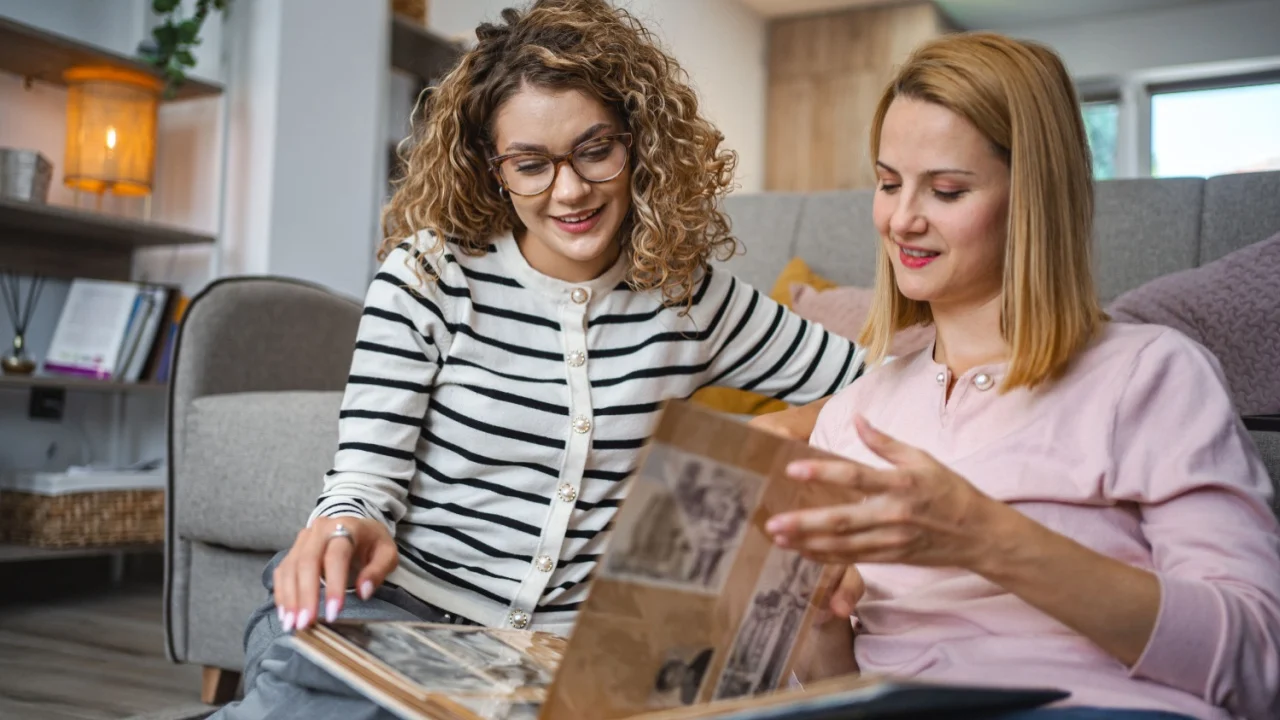 Two female friends looking at an old photo album at home