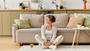 Senior woman sits comfortably on the floor in her cozy home, enjoying a peaceful moment.