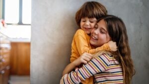 Happy siblings hugging, feeling love and connection, kid girl sister embracing little boy brother