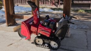 Takayama, Feb 07, 2016: A Honda HYBRID snow blower, painted bright red, is stored under a traditional wooden structure, ready for use during the heavy winter snowfall season.