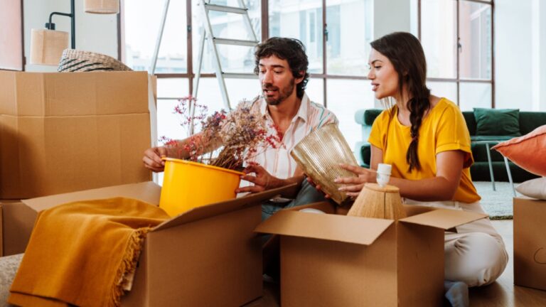 Happy young couple relocating in a new apartment. Young woman and man working and arranging the new property they just bought. Moving stuff and boxes together.