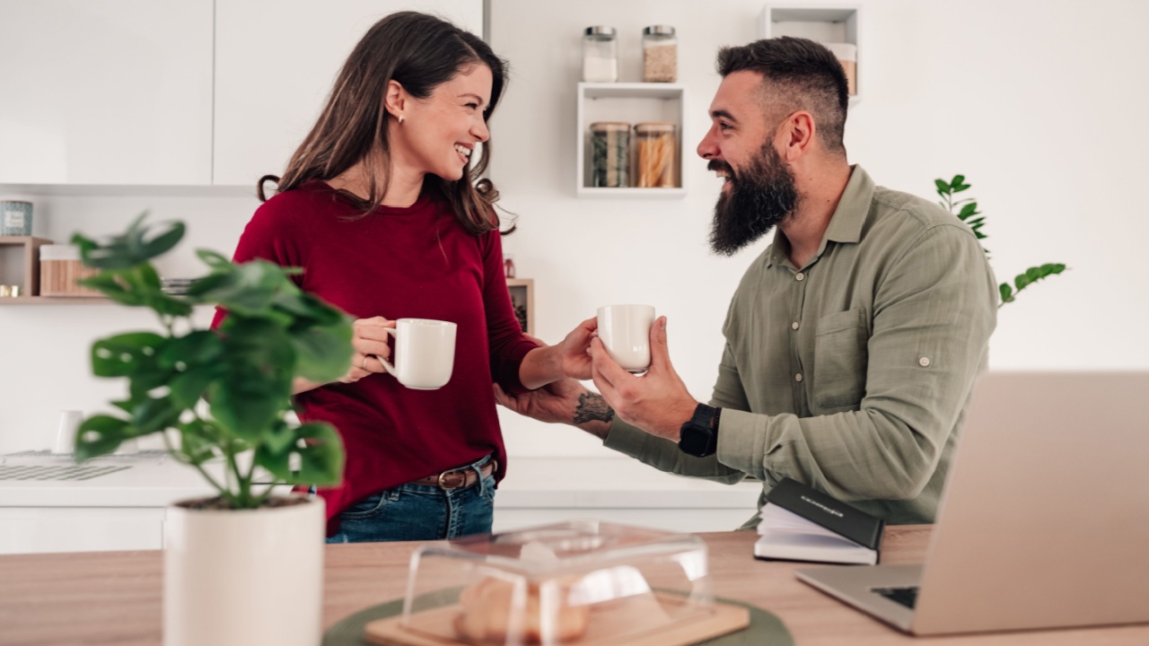 Cheerful diverse couple at home, sharing a moment with coffee, finding balance between work and life