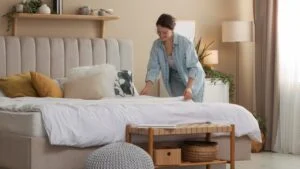 Professional decorator making bed in stylish bedroom